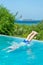 boy diving in the turquoise water of a swimming pool. a wonderful tropical island in the background