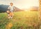 Boy and dog run together on the field with haystacks