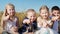 Boy with down syndrome sneezes sitting near to friends in wheat field, children show fingers at the camera and smiling