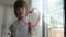 Boy draws heart with pink paint and brush on window glass