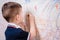 Boy draws on the wall with colored chalk. The child is engaged in creativity at home