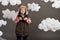 Boy dressed as an airplane pilot stands between the clouds and looks through binoculars