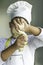 Boy dressed as a cook makes bread with fresh dough and covers his face