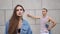 Boy dressed in pink shirt stands behind a seductive woman in jeans jacket