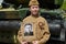 Boy dressed in Soviet military uniform during the second world war posing near army tank and holds portrait his grandfather who