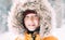 Boy dressed in Warm Hooded Casual Parka Jacket Outerwear walking in snowy forest cheerful smiling face portrait. Outdoor time and