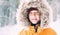 Boy dressed in Warm Hooded Casual Parka Jacket Outerwear walking in snowy forest cheerful smiling face portrait. Outdoor time and