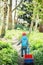 the boy is driving a red wagon along the path in the forest