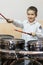 Boy drumming. boy in a white shirt plays the drums. A boy in a white shirt is drumming. Vertical photo