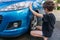 Boy earning pocket money cleaning blue compact car