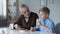 Boy eating cookies with milk, sharing with grandfather news from kindergarten