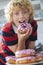 Boy Eating Iced Donut In Kitchen