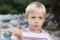 Boy eating in nature, on the river bank. Outdoor lifestyle, positive parenting, childhood experience concept