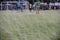 Boy elementary local soccer team practicing tactics and drilling on a green pitch with their coach after a school day in the eveni