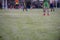 Boy elementary local soccer team practicing tactics and drilling on a green pitch with their coach after a school day in the eveni