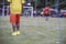 Boy elementary local soccer team practicing tactics and drilling on a green pitch with their coach after a school day in the eveni