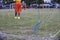 Boy elementary local soccer team practicing tactics and drilling on a green pitch with their coach after a school day in the eveni