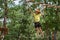 Boy enjoys climbing in the ropes course adventure. Happy boys playing at adventure park holding ropes and climbing wooden stairs