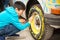 The boy enthusiastically paints the wheel of an old broken machine with paints