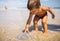 A boy examines a stranded jellyfish under the bright summer sun