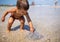 A boy examines a stranded jellyfish under the bright summer sun