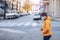 Boy with face mask and yellow jacket walking in the city with phone in hand.