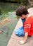 Boy feeding Japanese koi fish in tropical pond