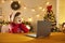Boy in festive Santa costume feeling surprised during watching Christmas movie on laptop