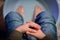 A boy with fingers crossed hands relaxing at home and worming his feet in hot salt water in the plastic wash bowl.