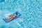 A boy floats on an inflatable colored mattress