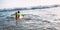 Boy floats on surf board towards the waves