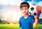 Boy is a football goalkeeper wearing gloves and holding a soccer ball with city background copyspace