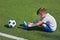 Boy football soccer tying laces him boots on grass
