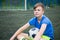 Boy footballer sitting on field