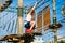 Boy in forest adventure park. Kid in orange helmet and white t shirt climbs on high rope trail. Climbing outdoor, amusement center