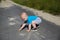 A boy gets up from an asphalt road after a fall, the theme of child injuries