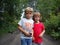 A boy and a girl are brother and sister. Children with blond hair walk next to trees and bushes. Girl with glasses and a red t-