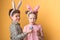 A boy with a girl with bunny ears hold Easter eggs in his hands