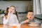 Boy and girl children in the kitchen eating sausages with pasta is very fun and friendly