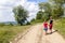 A boy and a girl children walk on a dirt road on a sunny summer day. Kids holding hands together while enjoying ativity outdoors.