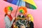 A boy and a girl in a clown wig stand next to a funny wig-wearing Christmas tree under a colored umbrella