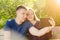 Boy and girl doing sitting on bench in the park selfie on the tablet on summer sunny day