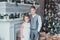 Boy and girl dressed elegantly standing in a bright room by the fireplace. Christmas tree in the background. New year concept