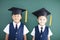 boy and girl in graduation cap stand before chalkboard
