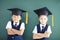 boy and girl in graduation cap stand before chalkboard