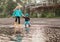 Boy and girl jumping in puddle in waterproof coat and rubber boots