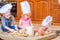 Boy and girl and a newborn kid with them in chef`s hats sitting on the kitchen floor soiled with flour