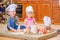 Boy and girl and a newborn kid with them in chef`s hats sitting on the kitchen floor soiled with flour