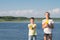 Boy and girl play water pistols against the blue lake and sky