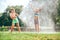 Boy and girl playing in garden, pouring with water each other from the hose, making a rain. Happy childhood concept image